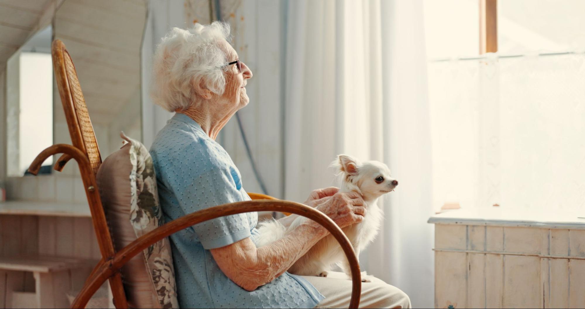 woman-receiving-in-home-hospice-care-petting-therapy-dog-while-looking-out-window
